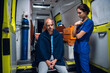 © Anna Kosolapova - Nurse standing beside a patient who is sitting on the edge of an ambulance car.