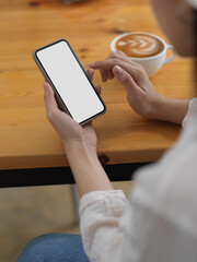 Female using smartphone on wooden table with coffee cup, clipping path