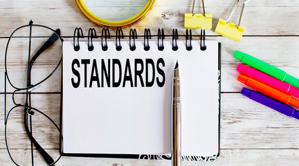 Poster - STANDARDS written in a notebook on white background with office tools
