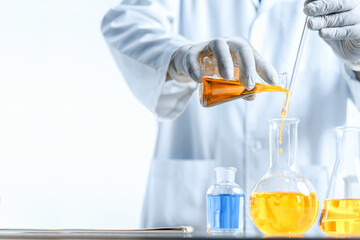 Wall Mural - hand of scientist holding flask with lab glassware in chemical laboratory background, science labora