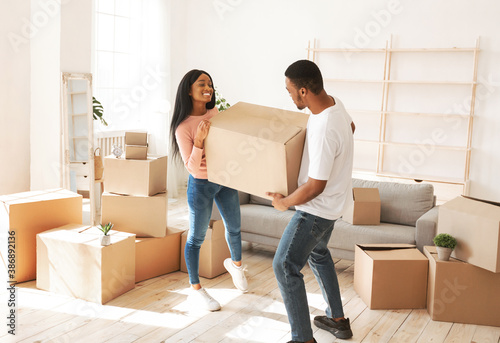 Cuadros en Lienzo Happy African American woman and her husband carrying cardboard box with their p