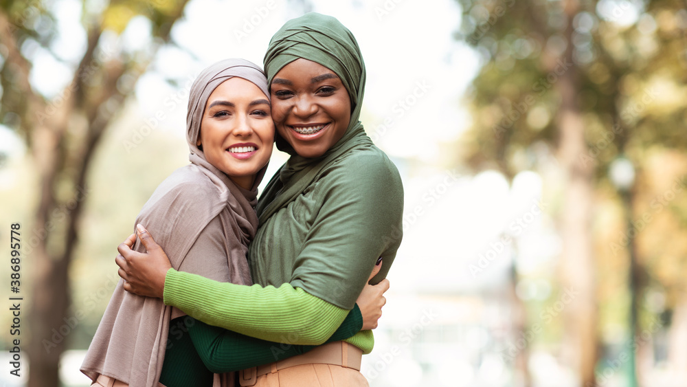 Two Muslim Ladies In Hijab Hugging Posing Standing In Park - obrazy, fototapety, plakaty 
