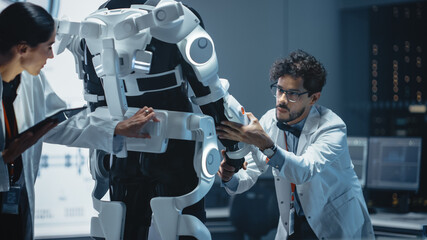 Poster - In Robotics Development Laboratory: Chief Female Engineer and Top Male Scientist Work on a Bionics Exoskeleton Prototype. Designing Powered Exosuit to Help Disabled People Walk, Workers Lift Goods