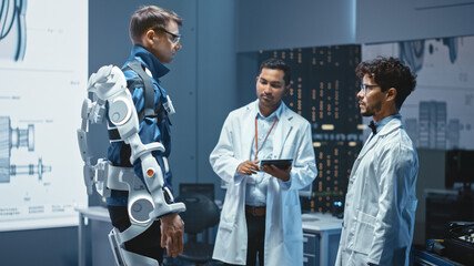 Poster - In Robotics Development Laboratory: Engineers and Scientists Work on a Bionics Exoskeleton Prototype with Person Testing it. Designing Wearable Exosuit to Help Disabled People, Warehouse Workers