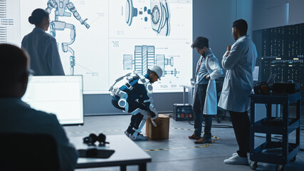 Poster - In Development Laboratory: Engineers Look at Robotics Exoskeleton Prototype Presentation with Person Testing it, Lifting Heavy Carboard Box. Designing Wearable Exosuit to Help Warehouse Workers