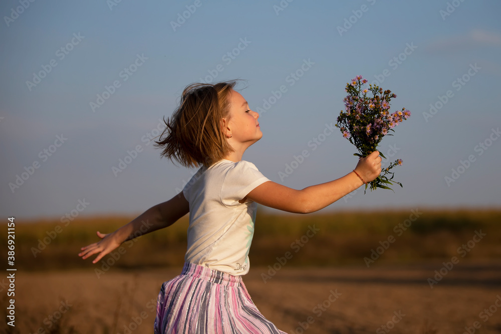 Beautiful little girl in the meadow with a bouquet of flowers. A child ...
