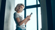 © Strelciuc - Busy caucasian woman with blonde hair is chatting on phone while wear a mask near the window