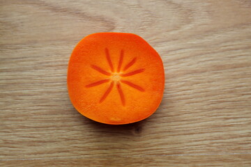 Orange persimmon in a cut on a wooden background.