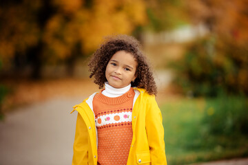 Wall Mural - Cute afro girl smiling broadly outdoors and enjoying autumn day in park.