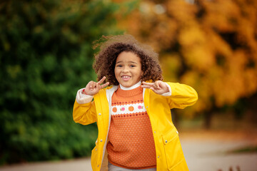 Wall Mural - Cute afro girl smiling broadly outdoors and enjoying autumn day in park.