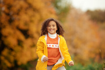 Wall Mural - Cute afro girl smiling broadly outdoors and enjoying autumn day in park.