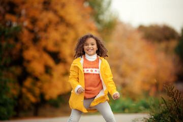 Wall Mural - Cute afro girl smiling broadly outdoors and enjoying autumn day in park.