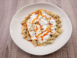 Turkish Manti with red pepper, tomato sauce, yogurt and mint. Plate of traditional Turkish food