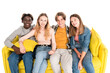 © LIGHTFIELD STUDIOS - Positive multiethnic teenagers looking at camera while sitting on yellow couch isolated on white
