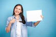 © KomootP - Pretty young woman holding empty blank paper and finger point for advertising banner on colorful background