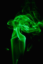 Whimsical Curls And Shapes Of Green Smoke On A Dark Background. Streaming Smoke From A Burning Incense Stick.