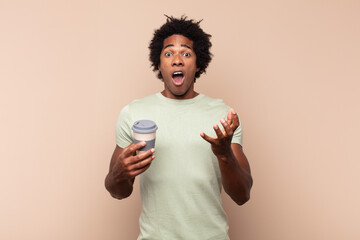 Wall Mural - young black afro man feeling extremely shocked and surprised, anxious and panicking, with a stressed and horrified look