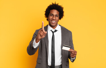 Wall Mural - young black afro man smiling proudly and confidently making number one pose triumphantly, feeling like a leader