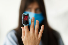 Pulse Oximeter on  finger, adult female in face mask measuring blood oxygen level