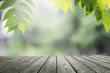 Wall Mural - Wooden table and empty blurred green leaves nature background for product.