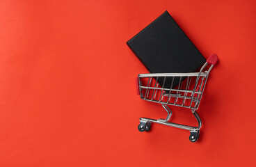 Shopping trolley with gift box on red background