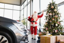 New Car As A Christmas Present. Santa Claus In The Car Showroom Near A New Car.