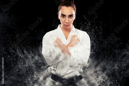 Portrait of sporty karate and taekwondo woman in white kimono with black belt on dark background Lerretsbilde