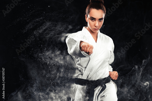 Portrait of sporty karate and taekwondo woman in white kimono with black belt on dark background Lerretsbilde
