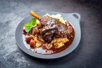 Wall Mural - Modern style traditional braised slow cooked lamb shank in red wine sauce with shallots and mashed potatoes offered as top view in a design cast iron plate with copy space