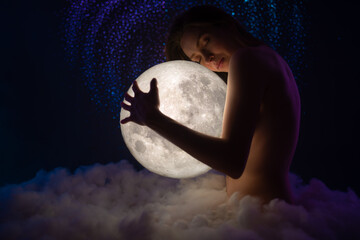 Wall Mural - beautiful young naked woman hugs the moon on amazing starry sky with and soft clouds hugs the moon. 