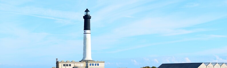 Wall Mural - White lighthouse of Ile de Sein in Brittany, France. Clear blue sky with cirrus clouds. Panoramic view. Idyllic landscape. Travel destinations, tourism, sightseeing, landmarks, vacations