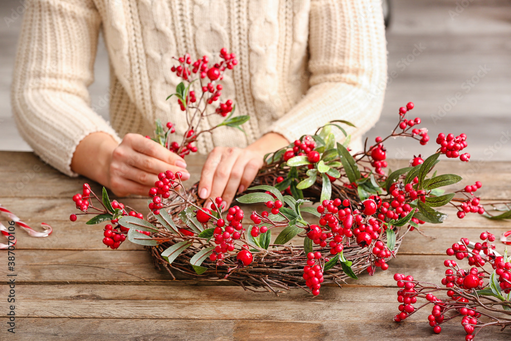 Woman making beautiful Christmas wreath at table