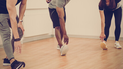 Wall Mural - Three happy multiethnic friends doing stretching exercise for legs