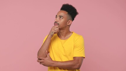 Sticker - Pensive smiling young african american man 20s years old in yellow t-shirt posing isolated on pastel pink background in studio. People lifestyle concept. Looking aside up put hand prop up on chin