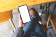 Top view mockup image of a woman holding mobile phone with blank white desktop screen