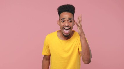 Sticker - Angry irritated displeased young african american man in yellow t-shirt posing isolated on pink background in studio. People lifestyle concept. Looking camera spreading hands clenching fist screaming