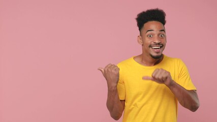 Sticker - Surprised shocked young african american man 20s years old in yellow t-shirt posing isolated on pink background studio. People lifestyle concept. Looking aside pointing fingers aside showing thumbs up