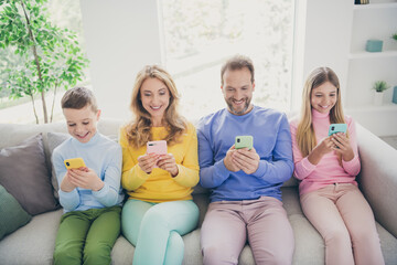 Poster - Full body photo of positive family people sit sofa mom dad two small kids use smartphone in house indoors