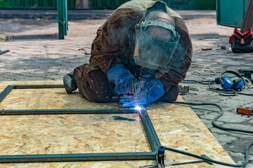 Wall Mural - An electric welder makes a metal structure by connecting a pipe with welding and an electrode.