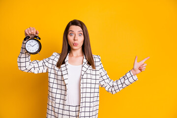 Photo of impressed funny brown hair woman plaid jacket hold bell pointing empty space isolated yellow color background