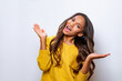 © Julia - Curly optimistic woman raises palms from joy, happy to receive awesome present from someone, shouts loudly, dressed in yellow sweater, on gray background. Excited Afro female yells