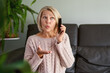 © JENOCHE - woman in a phone call sitting on a sofa in the living room in a house