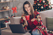 © deagreez - Photo of young woman sit couch laptop hold cup talk screen wear blanket red pullover jeans in decorated x-mas living room home indoors