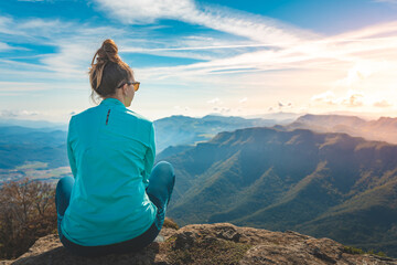 Woman traveler sitting in the edge of a cliff looking the mountains. Adventure solo traveling lifestyle. Wanderlust adventure concept. Active weekend vacations wild nature outdoor. Autumn fall forest.