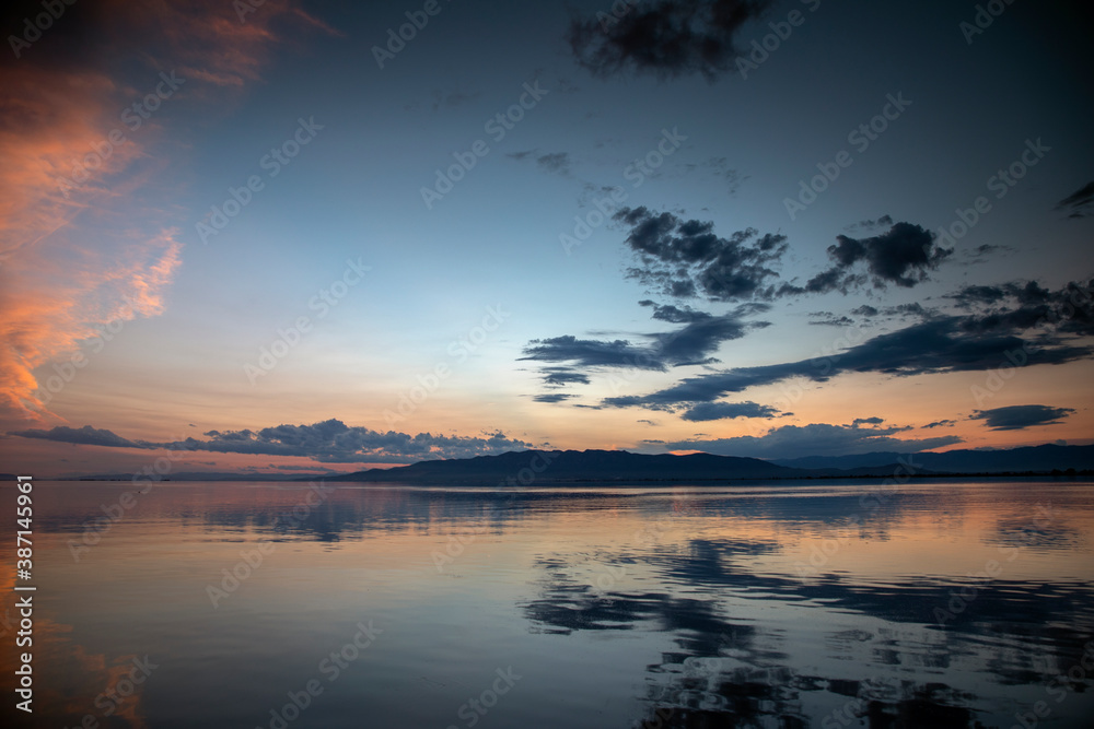 A sunset over water with clouds - obrazy, fototapety, plakaty 