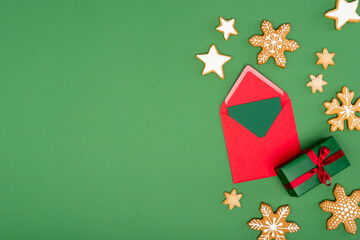 Canvas Print - top view of red envelope with card near baked snowflakes and stars on green background with copy space