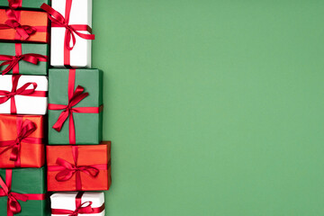 Wall Mural - top view of multicolored gift boxes with red ribbons on green background with copy space