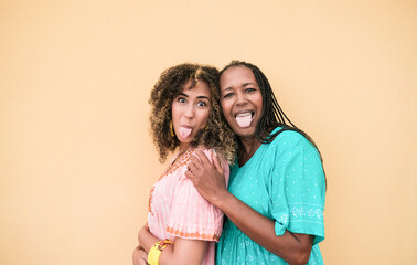 cheerful african mother and adult daughter doing a funny face with tongue out