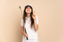 Young Ukrainian Golfer Girl Isolated On Beige Background With Fingers Crossing And Wishing The Best