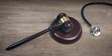 Close-up Of  Judge Gavel Beside Medical Stethoscope On Wooden Table. Panoramic Image.	